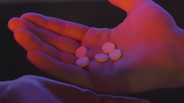 Close-up of Male Hand Pouring Pills in Female Palm. Unrecognizable Drug Dealer Trading Narcotics in alt