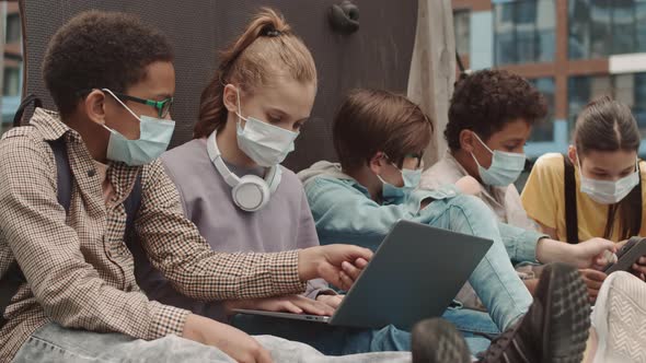 School Kids in Face Masks with Gadgets Outdoors alt