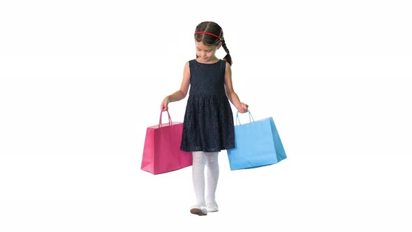 Beautiful Little Girl in Black Dress Walking with Shopping Bags on White Background alt