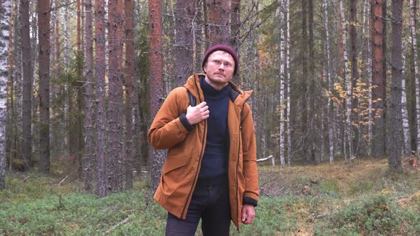 Caucasian Man Wearing Backpack Standing Over Forest Background