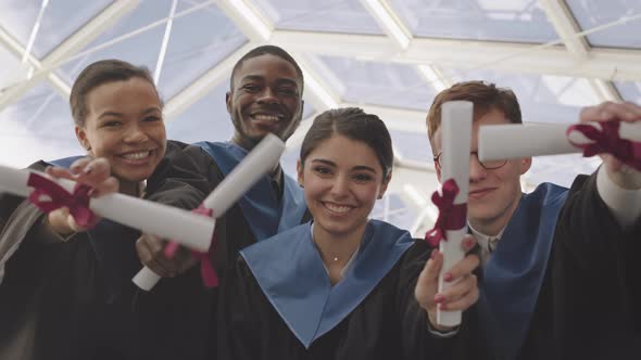 Four Diverse Cheerful Graduates Looking at Camera alt
