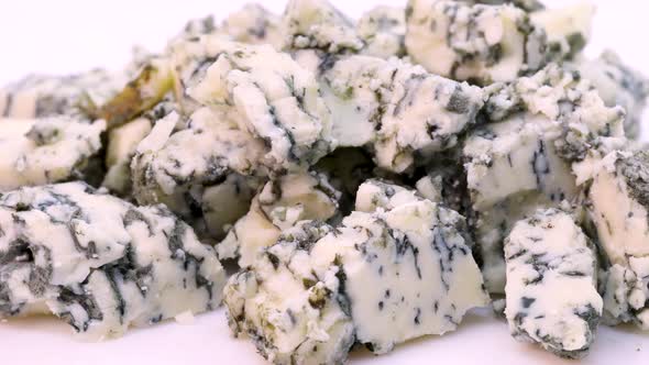 Gorgonzola cheese chopped in small pieces. Rotating close up view in 4k, macro shot. alt