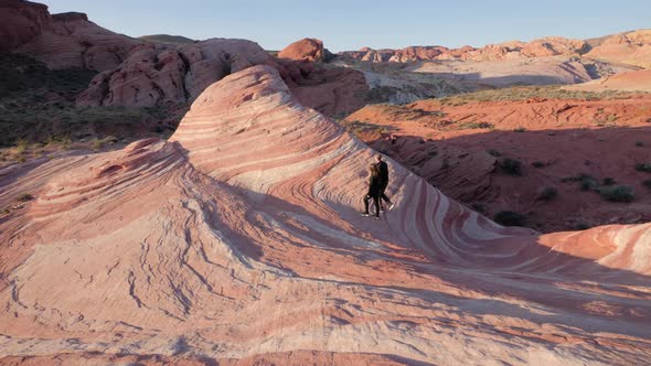 Young couple walking on Fire Wave during sunrise in Valley of Fire State Park, Nevada, USA alt