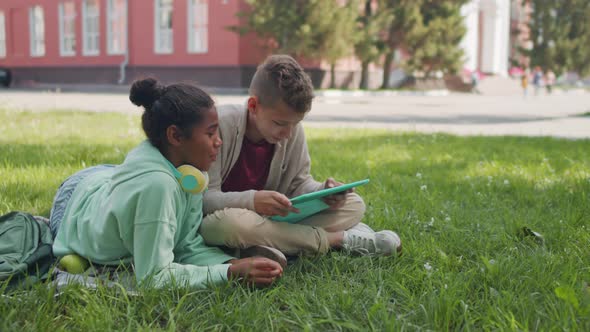 Schoolkids with Tablet Relaxing in Schoolyard alt