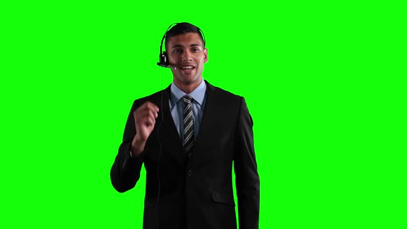 a mixed race in suit using an earpiece in a green background