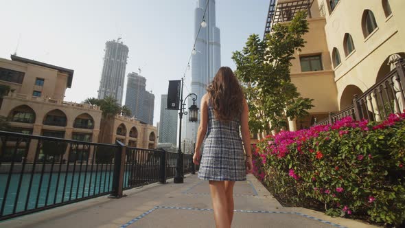 Woman Walking Through Luxury Apartment Complex Near Burj Khalifa Skyscraper in Dubai alt