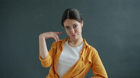 Portrait of Female Student Twisting Finger at Head Making Fool Sign Looking at Camera alt