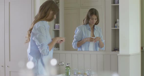 Woman looking into mirror and applying lipstick