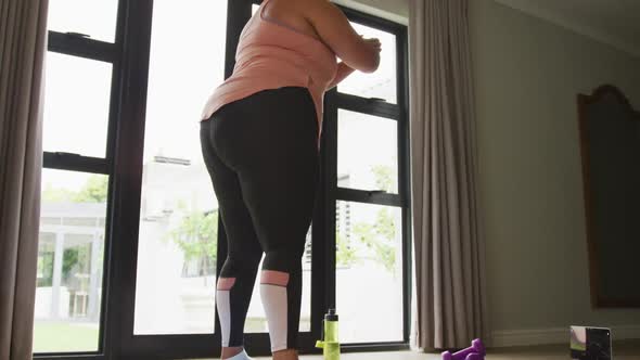 Video of plus size african american woman exercising at home, doing squats alt