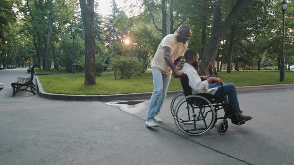 Mature Adult Black Man Walking in Summer Park with Paralyzed Nonmobile African Guy Men Having Fun on alt