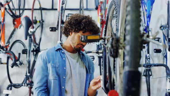 Mechanic repairing bicycle in workshop alt