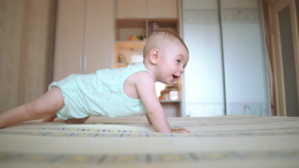 Cute Baby Crawls Onto the Bed, A Toddler in Pajamas. Sweet Face, Indoor Shot, Girl Infant