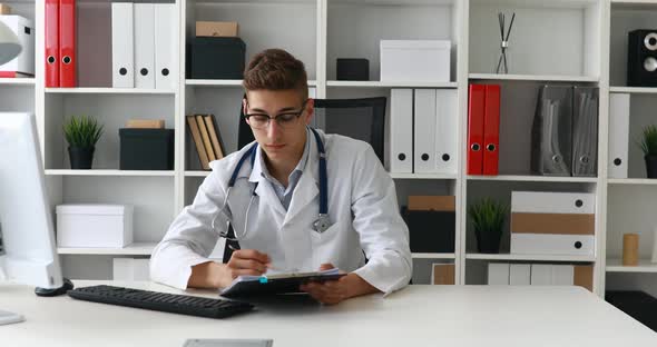 Young Doctor Working with Documents at Computer