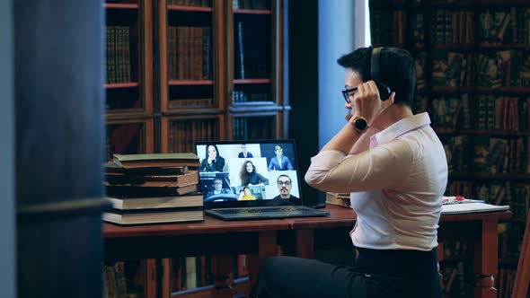 Teacher Putting on Headphones During an Online Class alt
