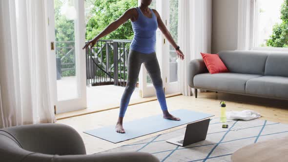 African american woman performing stretching exercise at home alt