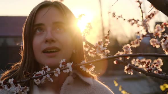 Girl Breathes Deeply of the Spring Flower after Quarantine at Spring Sunset