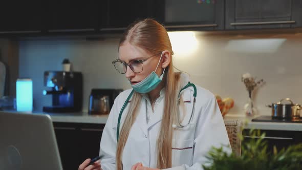 Female Doctor in Medical Gown Making Video Call to Patient From Home alt