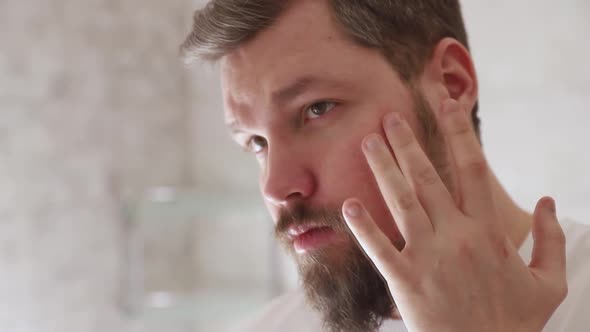 Portrait of Man in White Tshirt Applying Serum on His Face at Bathroom alt