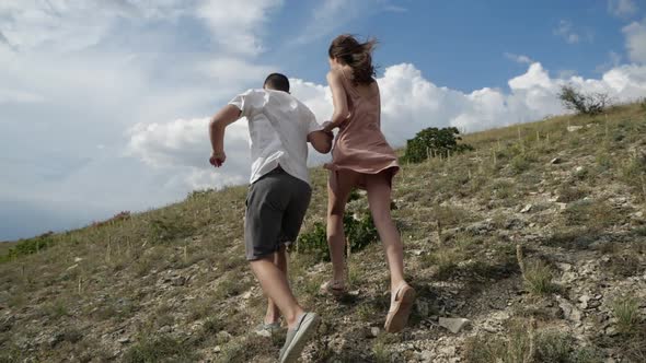 Young Couple Running Across the Plain Holding Hands