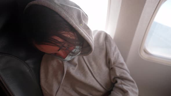 Tired Woman Passenger in Covid Safety Face Mask Sleeping in Seat at Window in Airplane alt