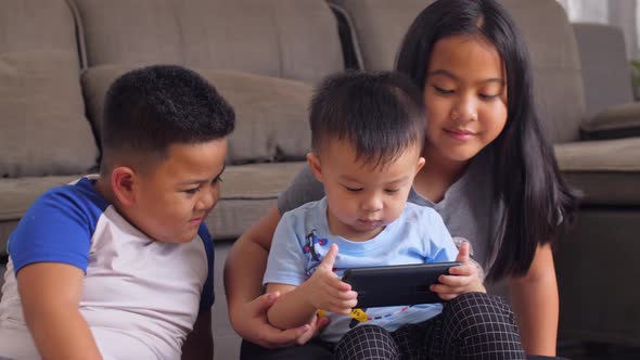 Asian Sister And Brothers Watching With Phone alt