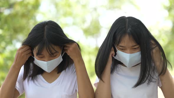 Two Young Asian women wearing protective facial mask in the forest alt