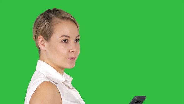Young beautiful woman writes an SMS on a Green Screen, Chroma Key. alt