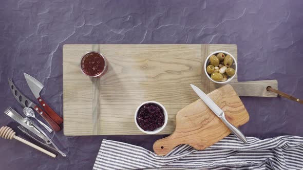 Flat lay. Arranging gourmet cheese, crakers, and fruits on a board for a large cheese board. alt