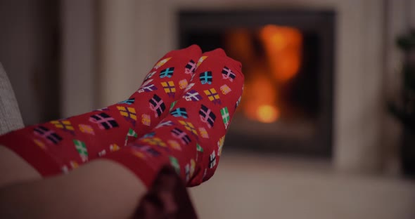 Woman Wearing Warm Wool Socks Lying By the Fireplace at Christmas alt