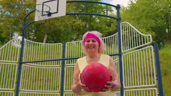 Senior Woman Grandmother Athlete Posing Playing with Ball Outdoors on Basketball Playground Court alt