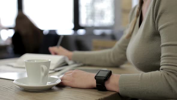 A business girl in a restaurant works with a tablet and drinks coffee. alt