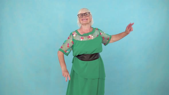 Fun Expressive and Energetic Old Woman Dancing on a Blue Background alt