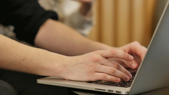 Hands touch typing on a laptop keyboard