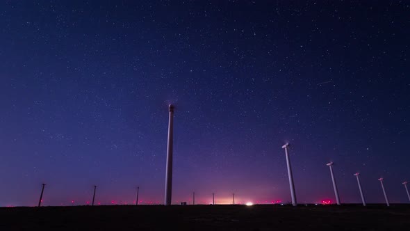 Time lapse with night starry sky above wind power farm alt
