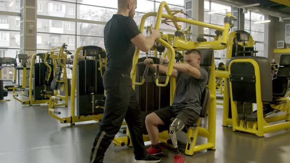 Disabled Young Man with Instructor Working Out in Gym