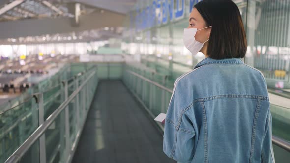 Woman passenger wearing face mask walking in airport terminal to boarding gate during the COVID19. alt