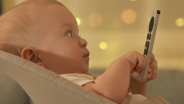 Caucasian Small Baby Watching TV at Home Cute Little Toddler Child Holding Remote Control for TV alt