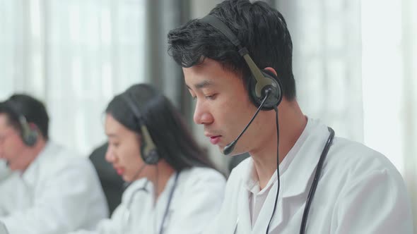 Asian Man Doctor With Colleagues Working As Call Centre Agent Speaking To Customer alt