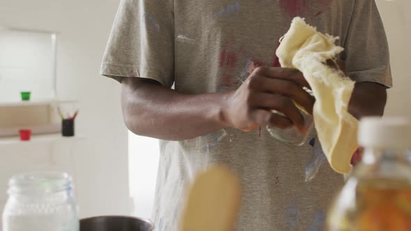 Mid section of african american male artist cleaning his hands at art studio alt
