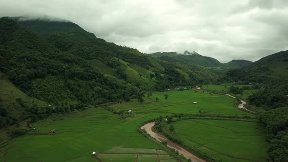 Aerial view flying above lush green tropical rain forest mountain with rain cloud cover during the r alt