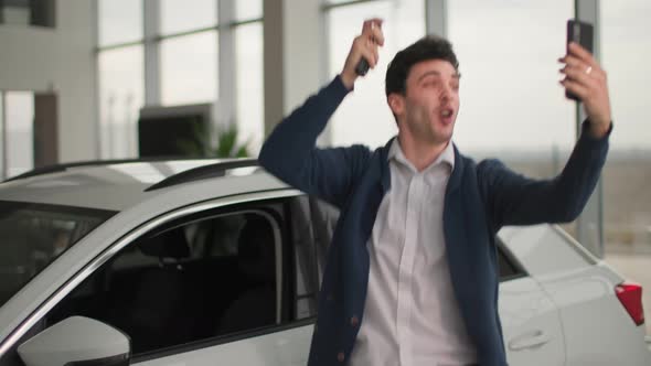 Buying Car Emotional Male Buyer with Keys to New Vehicle in His Hands Records Video on Smartphone