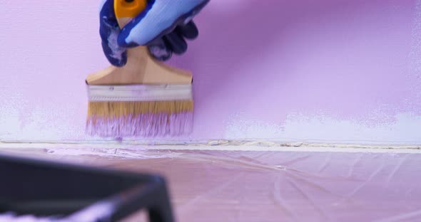 Person in Work Gloves Paints Hardtoreach Places of the Wall at Joint with a Large Brush Floor is
