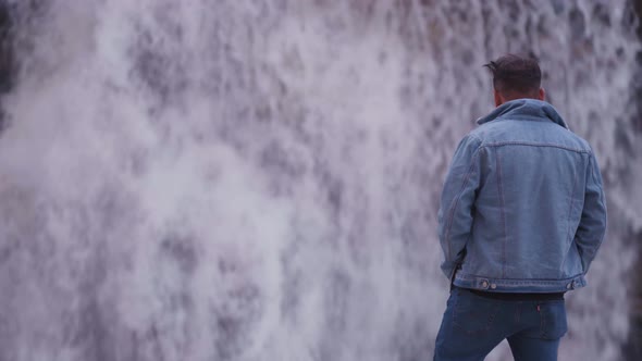 Young Indian Man standing on rock looking confidently at waterfall