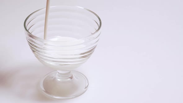 Organic Milkshake in a Glass Cup. A Person Pours Kefir Into Transparent Container in Isolation