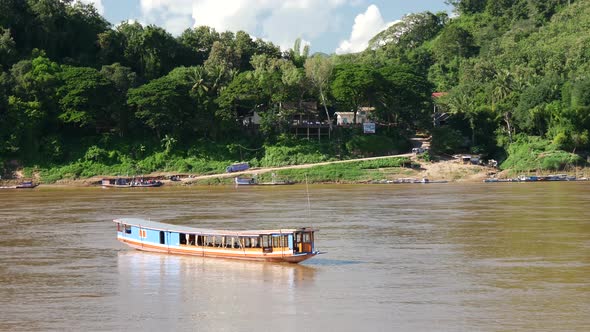 Long-tail boat moving at the current at the Mekong river in Luang Prabang alt