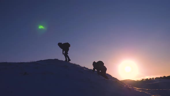 Tourists with Backpacks Help Each Other To Climb Top of Hill in Bright Rays of Sun. Climbers on a
