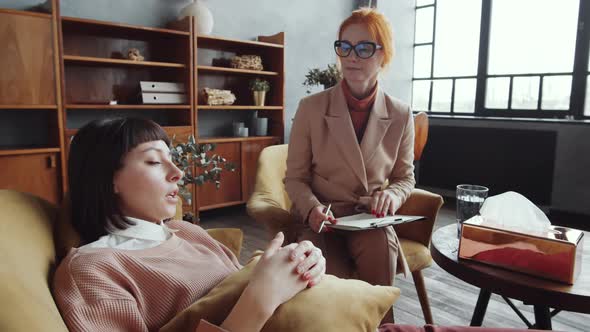 Frustrated Woman Lying on Sofa and Talking with Female Counselor alt