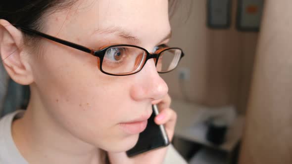 Woman in Glasses Is Speaking Mobile Phone and Looking Ahead
