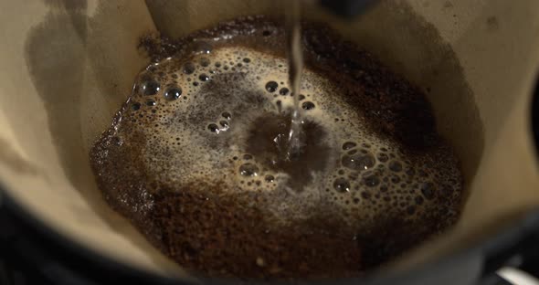 Dripping hot water over ground coffee in filter. Coffee brewing in slowmotion alt
