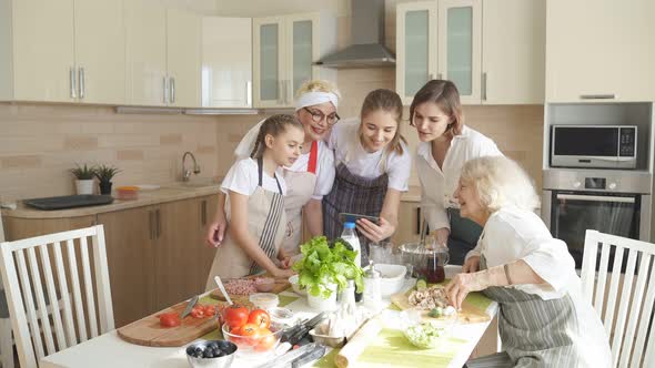Cheerful Family Grandmothers And Children Have Fun Watching Video While Cooking